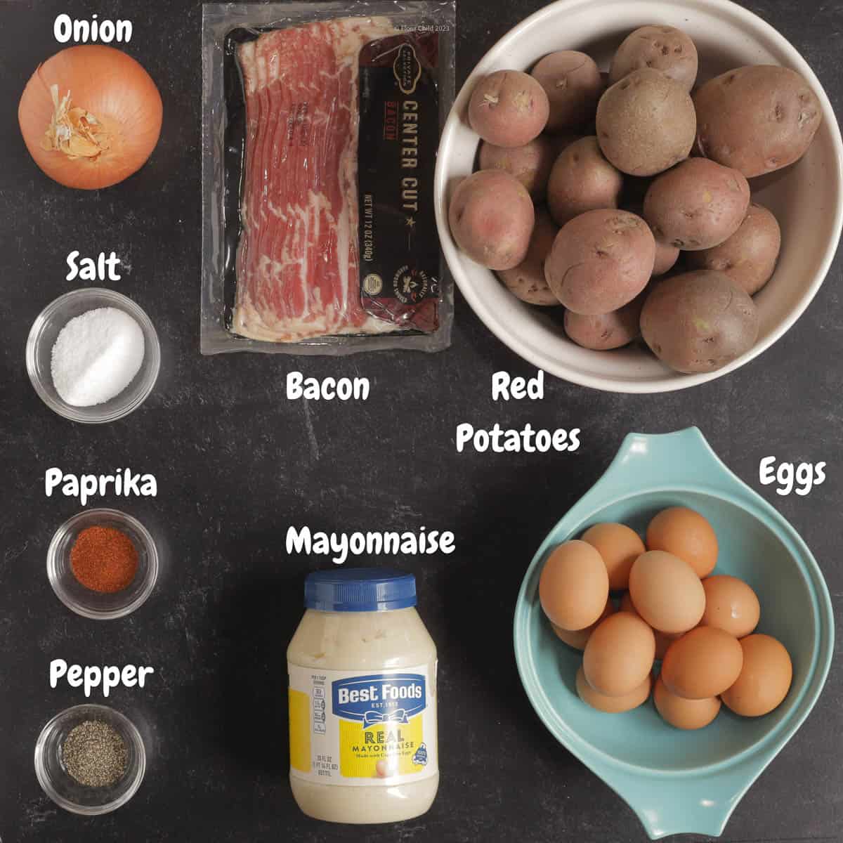 All of the ingredients for the classic potato salad recipe on a black background.