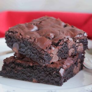 Two brownies stacked on top of each other on a white plate.