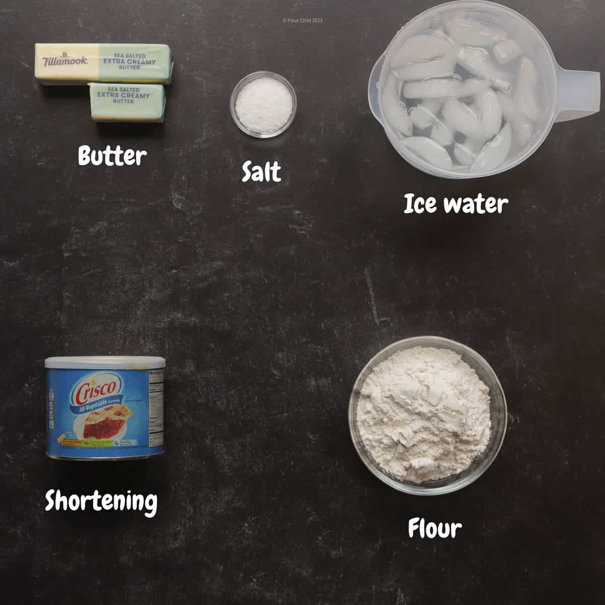 Ingredients for a double crust pie dough laid out on a black background.