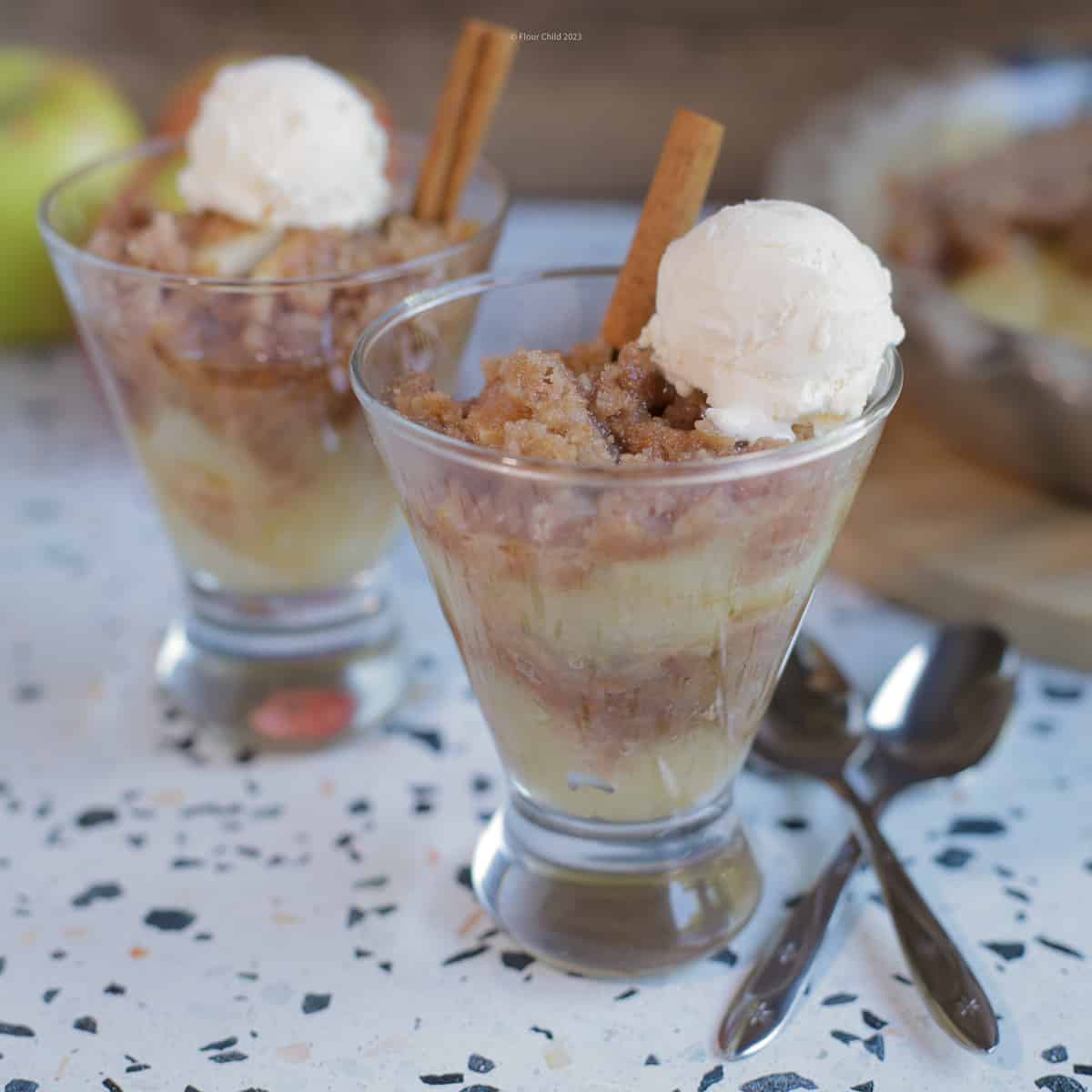 Apple Brown Betty in a parfait glass, with a scoop of ice cream and a cinnamon stick on top.