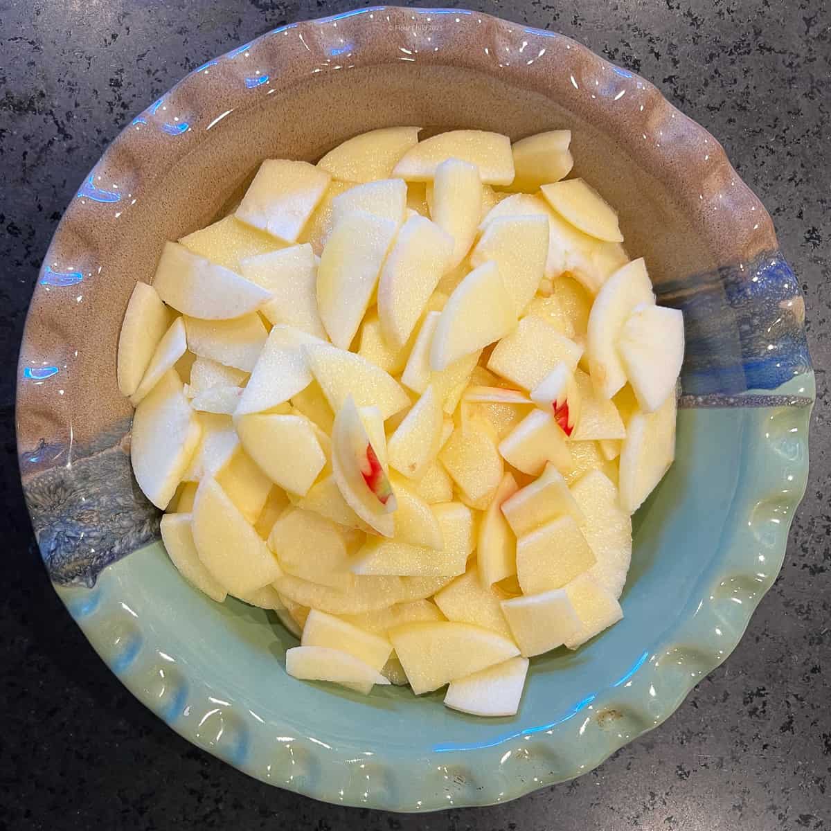 Three peeled and sliced apples in the bottom of a pie dish