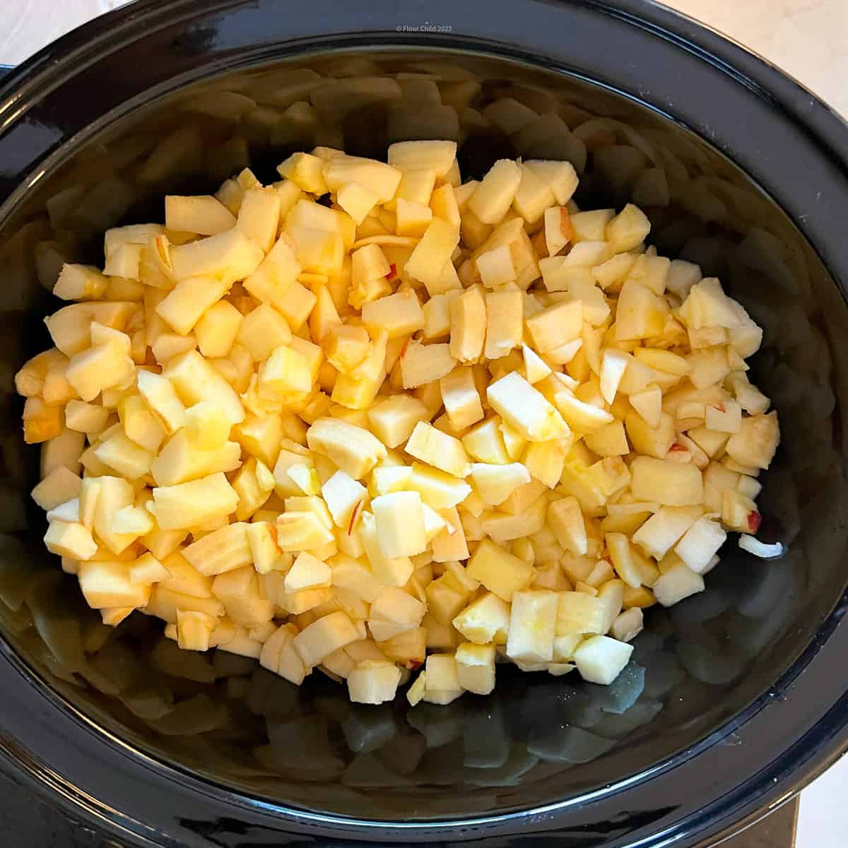 Apples in crockpot after they have been peeled, cored and diced.