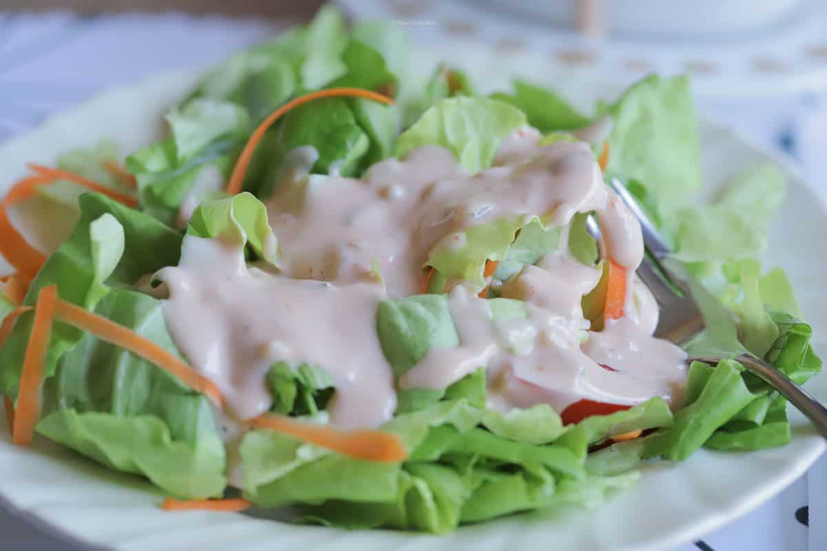 A tossed salad with thousand island dressing on the top.
