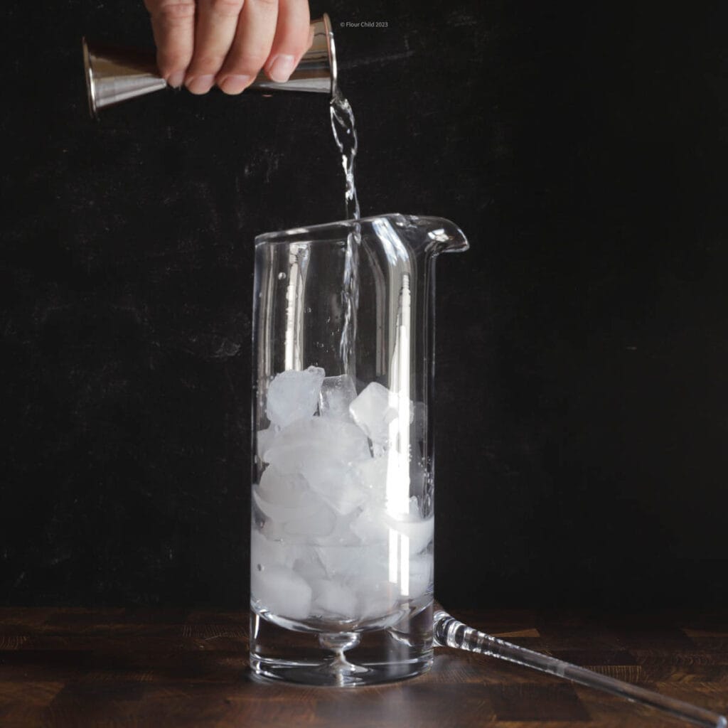 Pouring ingredients for a Gin Gibson into mixing glass and straining into a martini glass. 