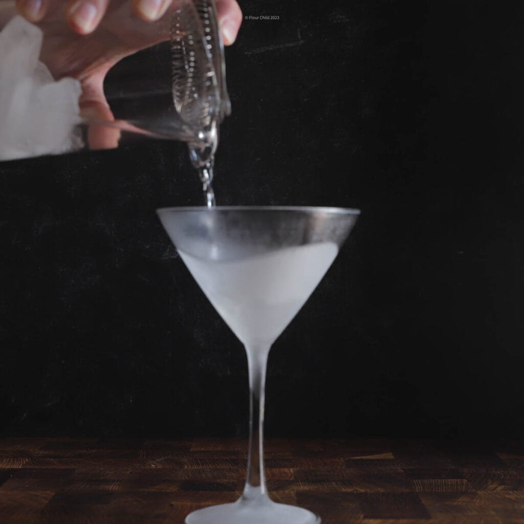 Pouring ingredients for a Gin Gibson into mixing glass and straining into a martini glass. 