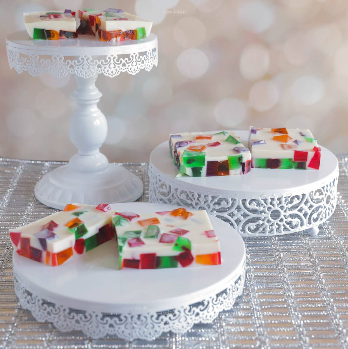 Stained glass jello squares on 3 round lattice serving trays of different heights.