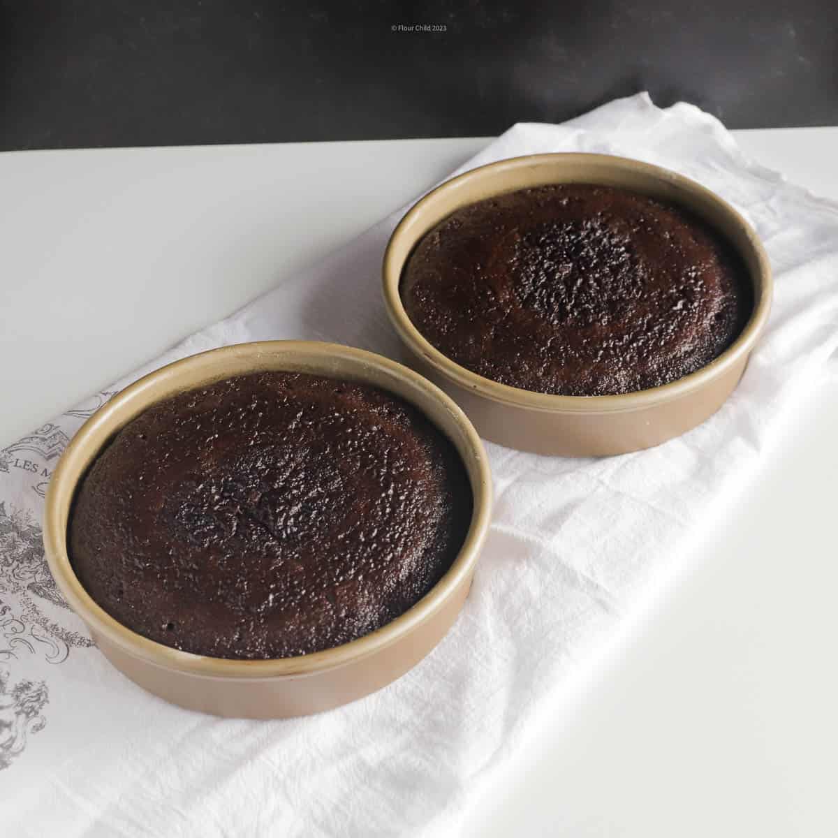 Two 8 inch round black magic cakes in cake pans, just taken out of oven.