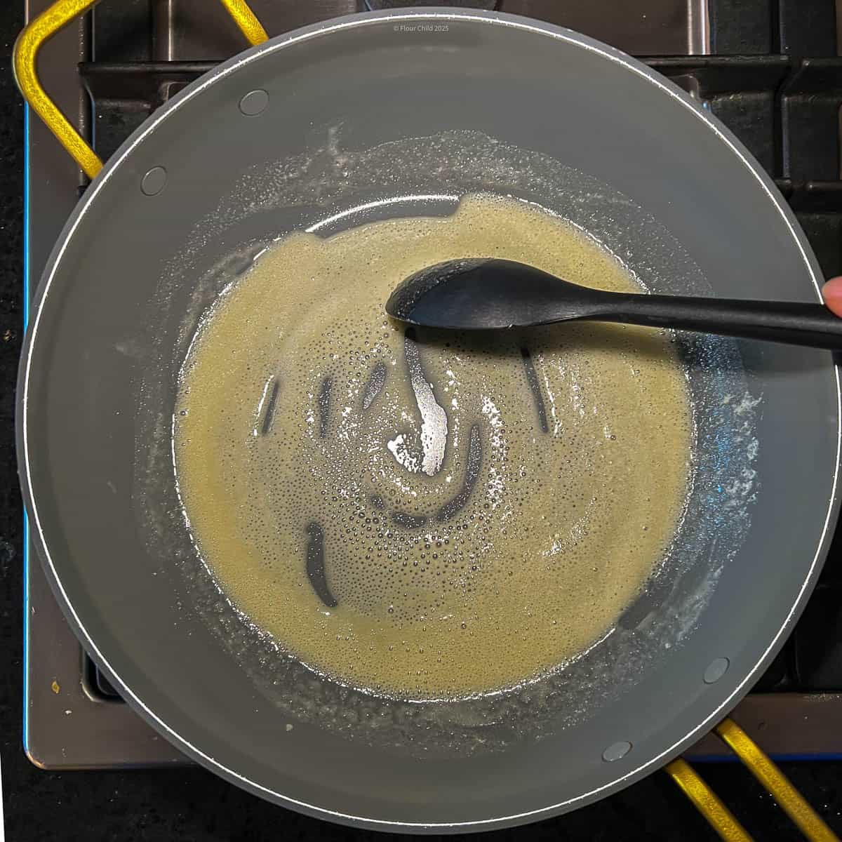 Stirring flour in with melted butter in frying pan.