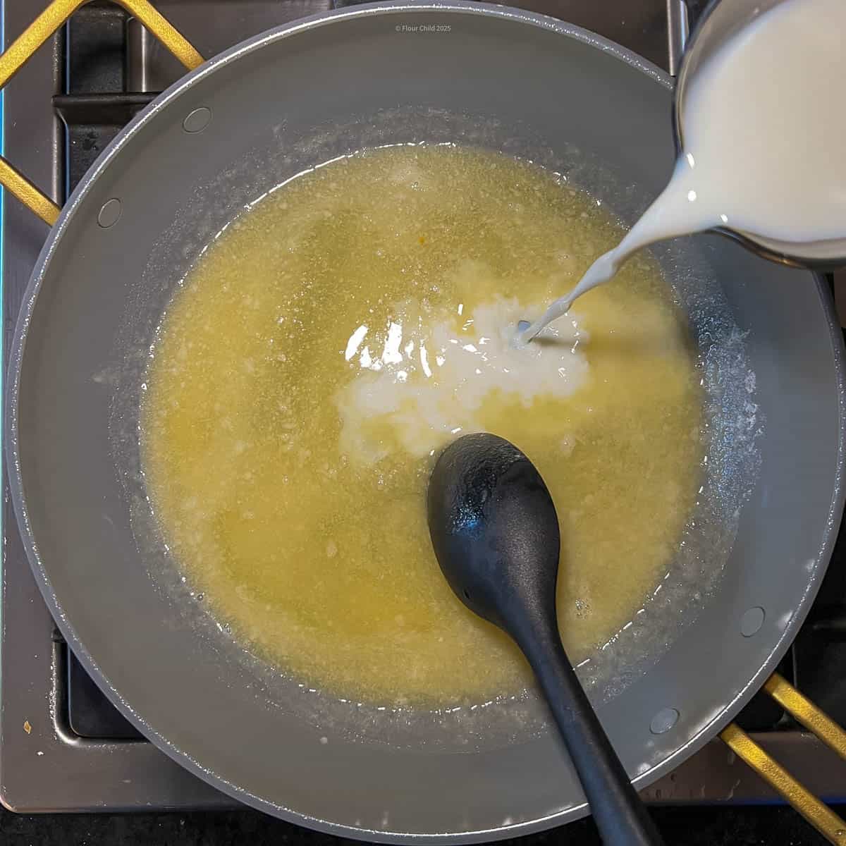 Pouring milk in skillet with other ingredients to create creamy base for casserole.