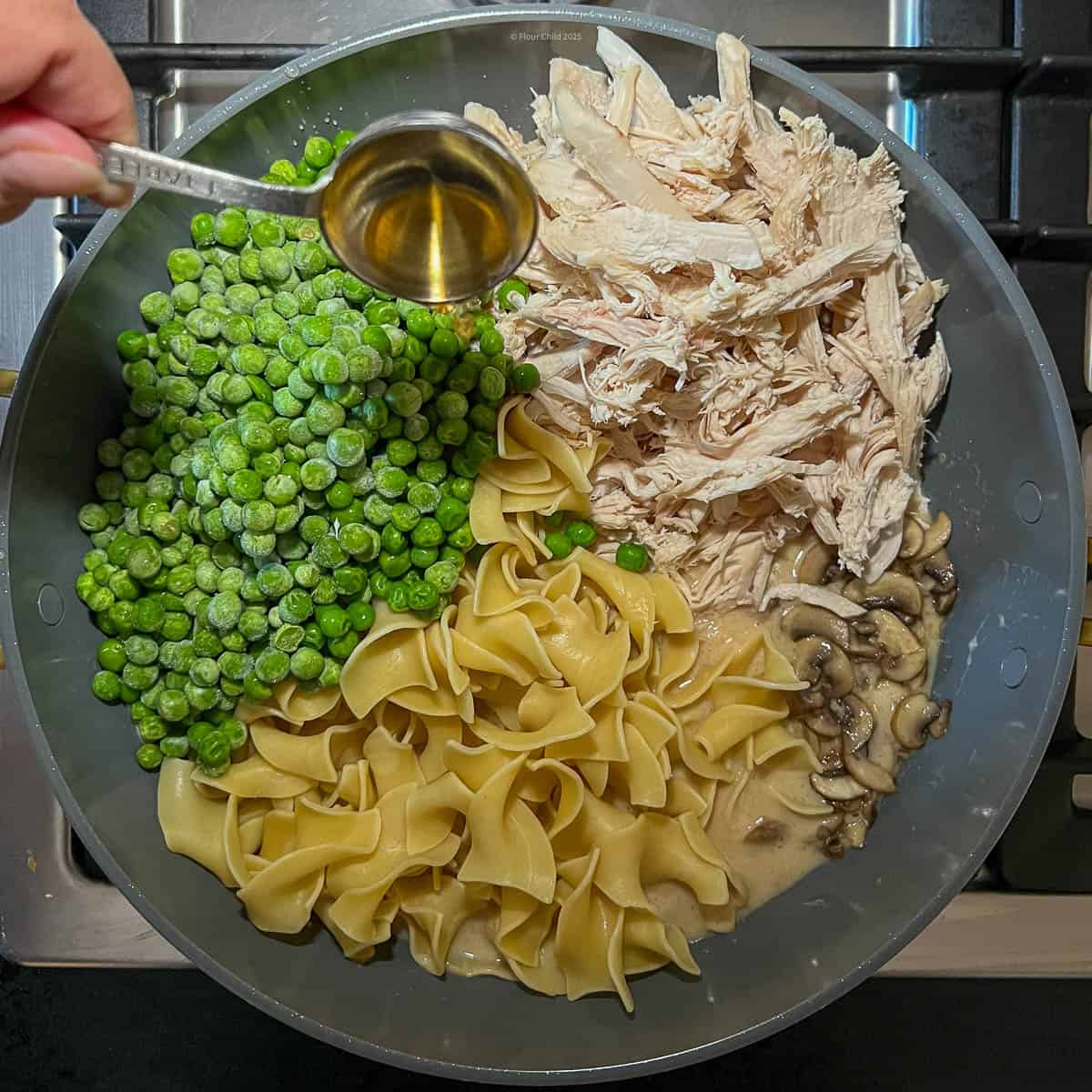 Cream sauce with chicken, mushrooms, peas, noodles, and sherry added in, prior to mixing.