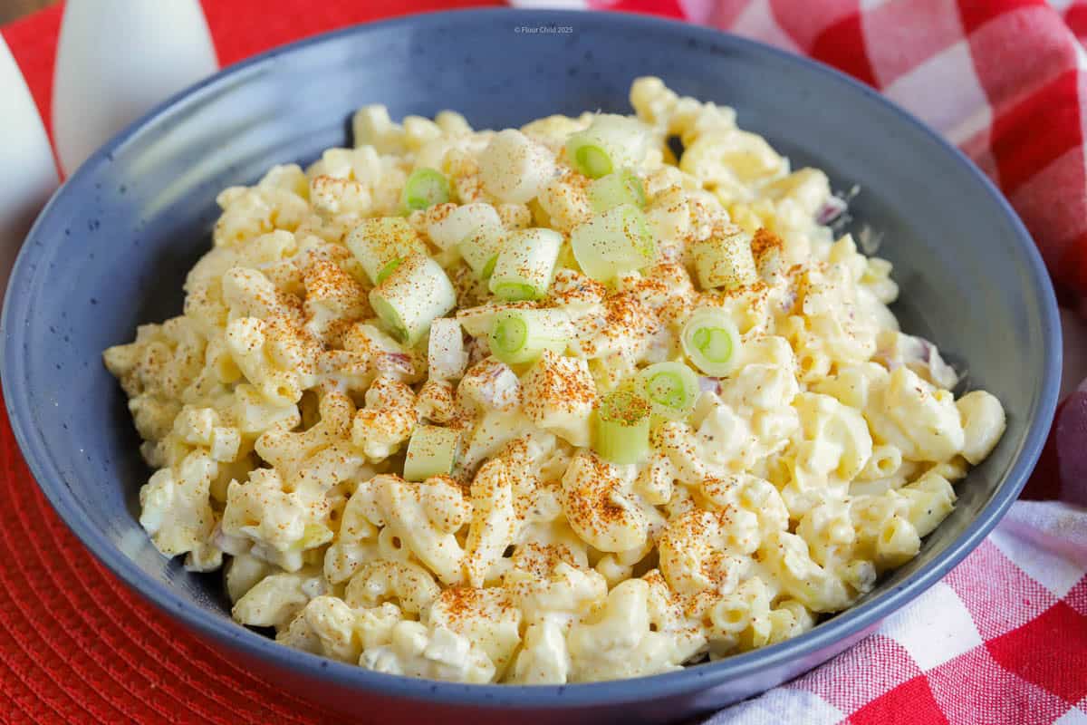 A blue serving bowl filled with deviled egg salad on a red background.