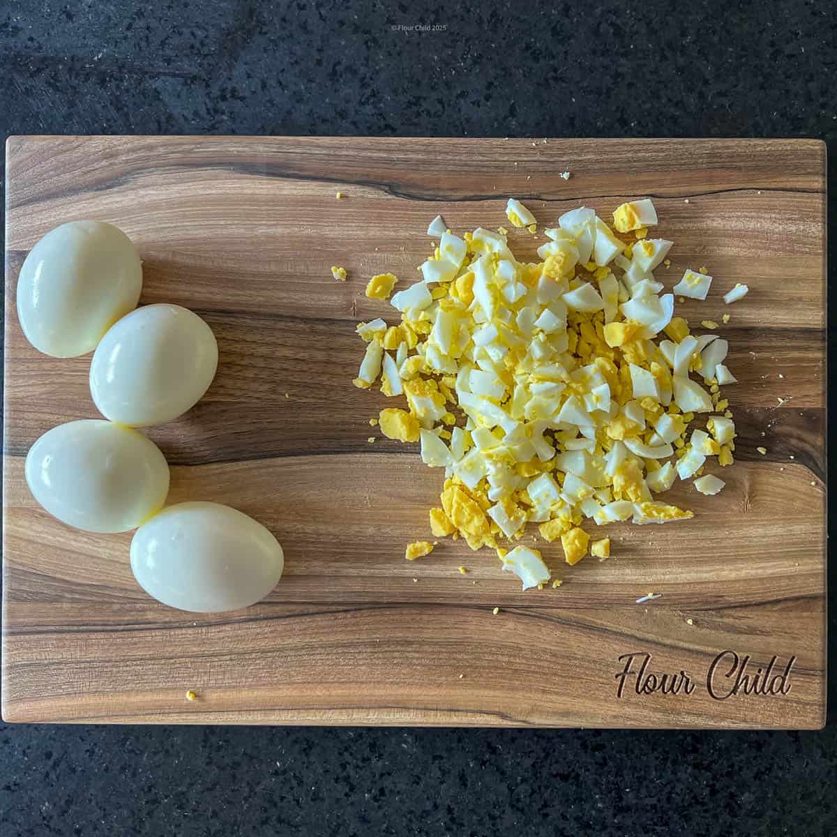 Eggs on a cutting board, being chopped into small pieces.
