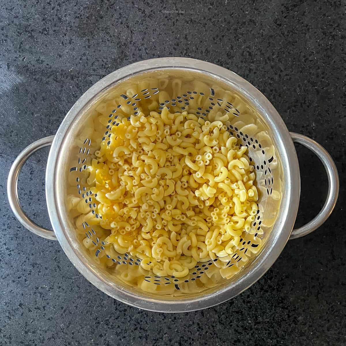 Macaroni noodles draining in colander.